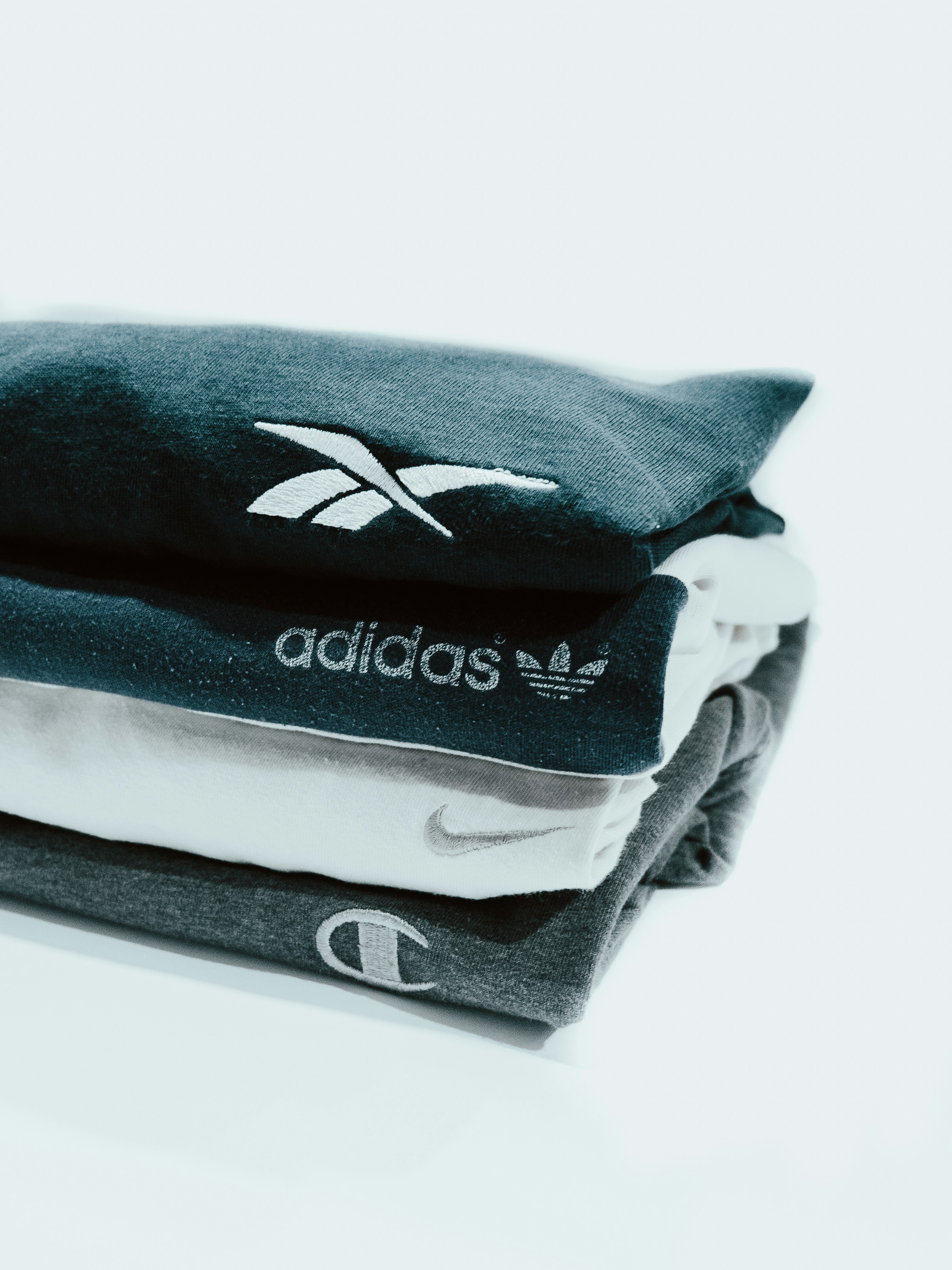 Stack of branded sportswear t-shirts (Reebok, Adidas, Nike, Champion)
